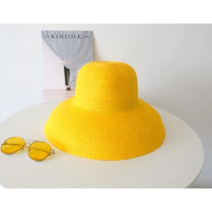 Detailed texture of yellow woven straw hat with large brim and matching sunglasses
