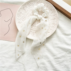 Detailed shot of white chiffon star scrunchie with long ribbons on a white ceramic plate