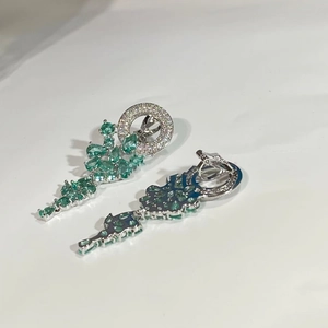 Détail de boucles d'oreilles pendantes en argent avec zircons verts et pavages