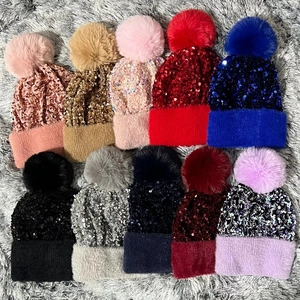 Detailed view of sequined knit hats with fluffy pom-poms in various vibrant colors