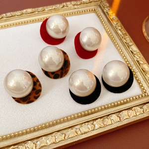 Detailed shot of three pairs of faux pearl earrings with red, leopard, and black felt bases