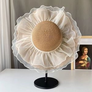 Close-up of a wide brim straw sun hat featuring white organza ruffle trim and natural texture