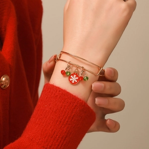 Close-up of adjustable gold Christmas bracelet with snowflake enamel charm on wrist