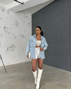 Full-body shot of light blue oversized denim jacket styled with white boots and shorts