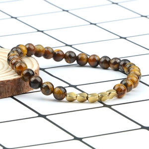 Natural tiger eye stone beaded bracelet with five golden heart charms on rustic wood slice