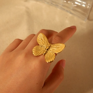 Bague papillon dorée imposante pour femme portée au doigt avec une finition métal brillant