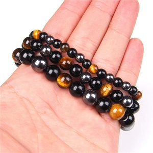 Close-up of hematite, obsidian, and tiger eye beaded bracelets held in hand for men