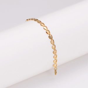 Polished gold heart link bracelet for women displayed on a white cylindrical stand