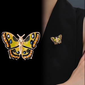 Fashionable butterfly brooch with yellow enamel and gold finish shown on dark clothing