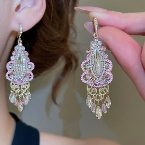 Detail of pink crystal drop tassel earrings with gold hollowed-out engraving and crystals