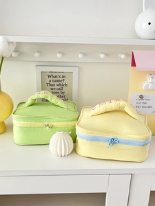 Quilted cosmetic bags in green and yellow with embroidered handles on a shelf