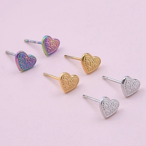 Detail of heart stud earrings in gold silver and rainbow with hammered metal texture