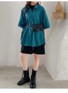 Peacock blue loose shirt paired with a black leather waist bag and gold ring buckle