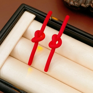Macro shot of red matte knot earrings in a black jewelry box with cream padding