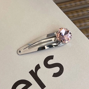 Macro detail of silver metal hair clip featuring a large faceted pink heart crystal