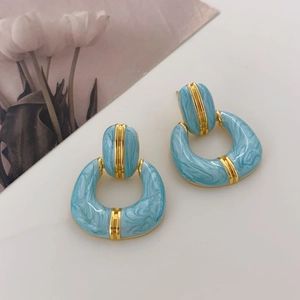 Detail of blue marble enamel earrings with gold-plated metal edges and oval ring design