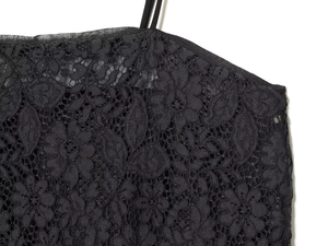 Detail of black lace fabric showing intricate floral patterns and thin shoulder straps