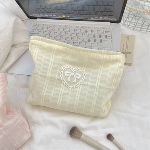 Detail of cream knitted makeup bag with delicate lace heart and ribbon bow decoration