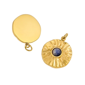 Detail of round gold pendant with sunburst texture and blue stone inlay on white background
