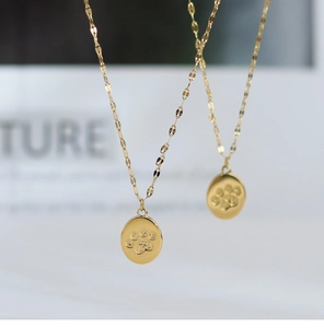 Macro view of gold cat paw print pendant necklace with fine engraved details