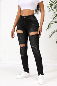 Détails du jean skinny noir avec déchirures et texture en denim usé sur le devant