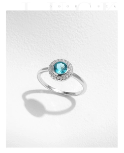 Close-up of s925 silver ring with round blue gemstone and halo of small diamonds