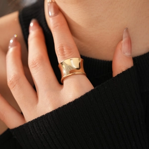 Close-up of a wide concave gold ring with a polished finish worn on index finger