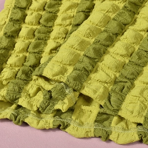 Detail van de groen-geel gestreepte seersucker stof met een 3D bubbel geplooide textuur