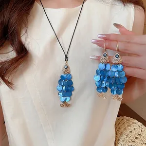 Bohemian gold necklace and earrings set with blue shell fish charms and evil eye detail