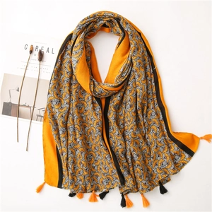 Detail of cotton-linen feel scarf featuring retro yellow floral patterns and orange tassels