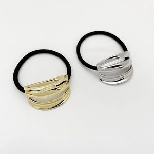 Detailed view of silver and gold curved hollow metal accents on black elastic hair ties