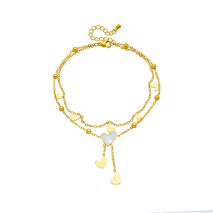 Layered gold heart anklet with shell pendant and beads on white background