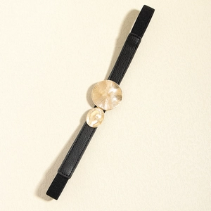 Close-up of black elastic belt with double gold circular buckles and sunburst texture