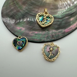 Detailed view of heart-shaped 18K gold-plated charms with shell inlay and rose motifs