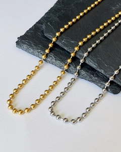Close-up of gold and silver beaded necklaces on a textured black slate background