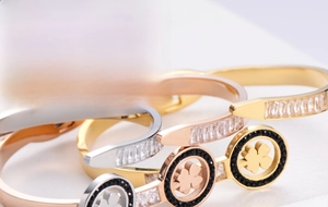 Primo piano di tre bracciali a quadrifoglio in oro rosa, oro e argento con zirconi