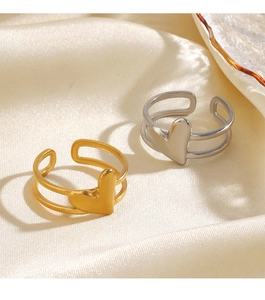 Detailed close-up of gold and silver heart-shaped open rings on soft beige silk