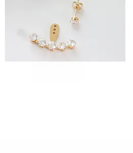 Detailed view of gold plated cubic zirconia ear jackets and stud earrings on grey background