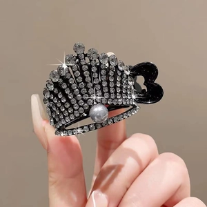 Macro shot of crown hair clip with rhinestones, grey pearl detail, and hand-held display