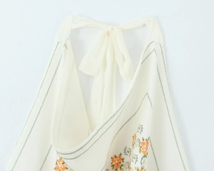 Close-up of the halter neck tie and orange floral print on a white chiffon top