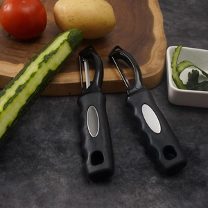 Kitchen peeler set on wooden board with fresh potato cucumber and rustic background