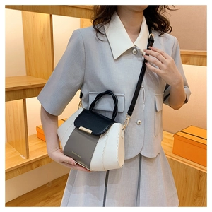 Woman in grey suit styling a tricolor patchwork crossbody bag with gold hardware detail