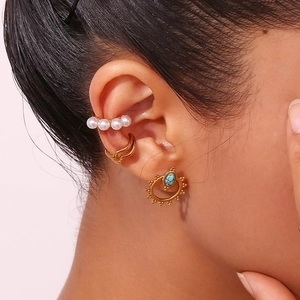 Close-up of bohemian turquoise sunflower stud earrings with pearl ear cuffs on ear