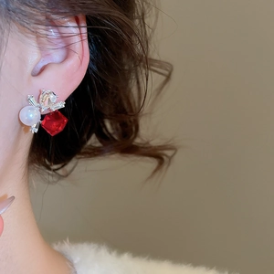 Close-up of elegant square red gem and pearl stud earrings worn on a model