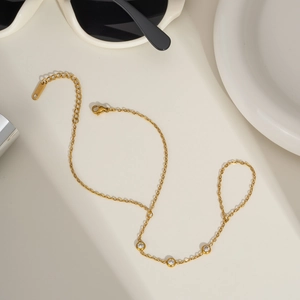 Elegant gold stainless steel finger bracelet with cubic zirconia on a minimalist background
