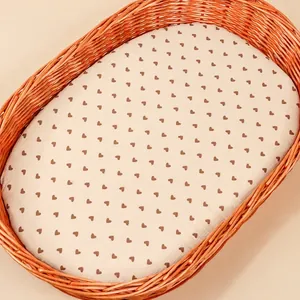 Close-up of baby fitted sheet with brown hearts on a soft cotton cradle mattress