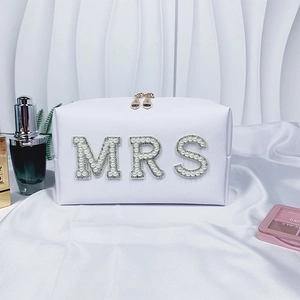 Detail of white bridal makeup bag featuring pearl and rhinestone MRS lettering