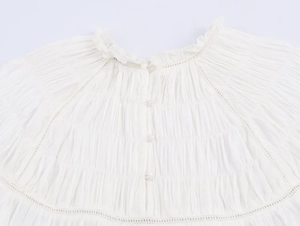 Detailed view of white poplin shirt with bead decoration and delicate lace edges
