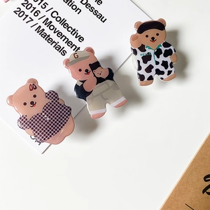 Detailed view of three cute cartoon bear phone socket grips in various poses and colors