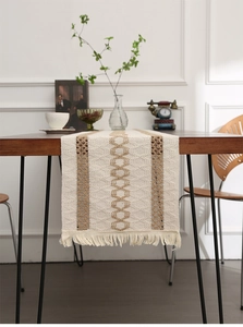 Detail of woven table runner featuring beige and brown geometric patterns and fringe